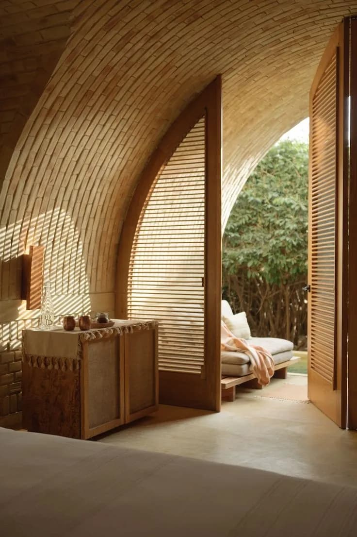 Interior de bóveda de ladrillo con celosía de madera abierta a la vegetación