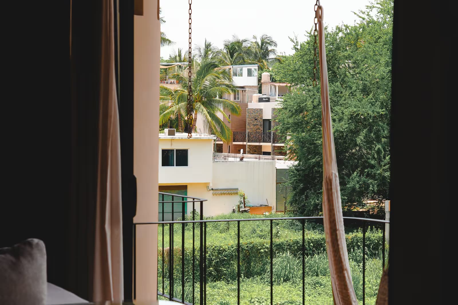 Balcón de un departamento en Puerto Escondido con hamaca y vista a las palmeras