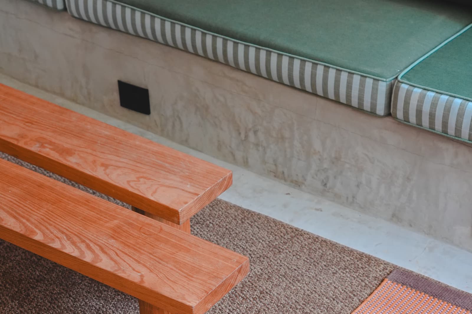 Interior de un hotel boutique con banca de madera y banca corrida verde