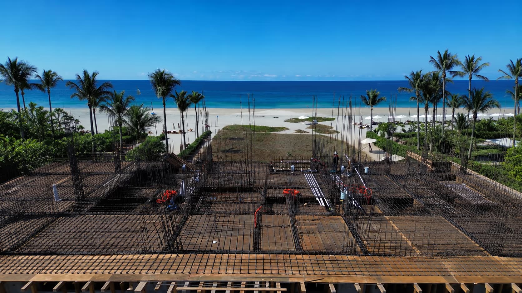Cimentación de varilla de una obra en construcción con palmeras y el mar al fondo